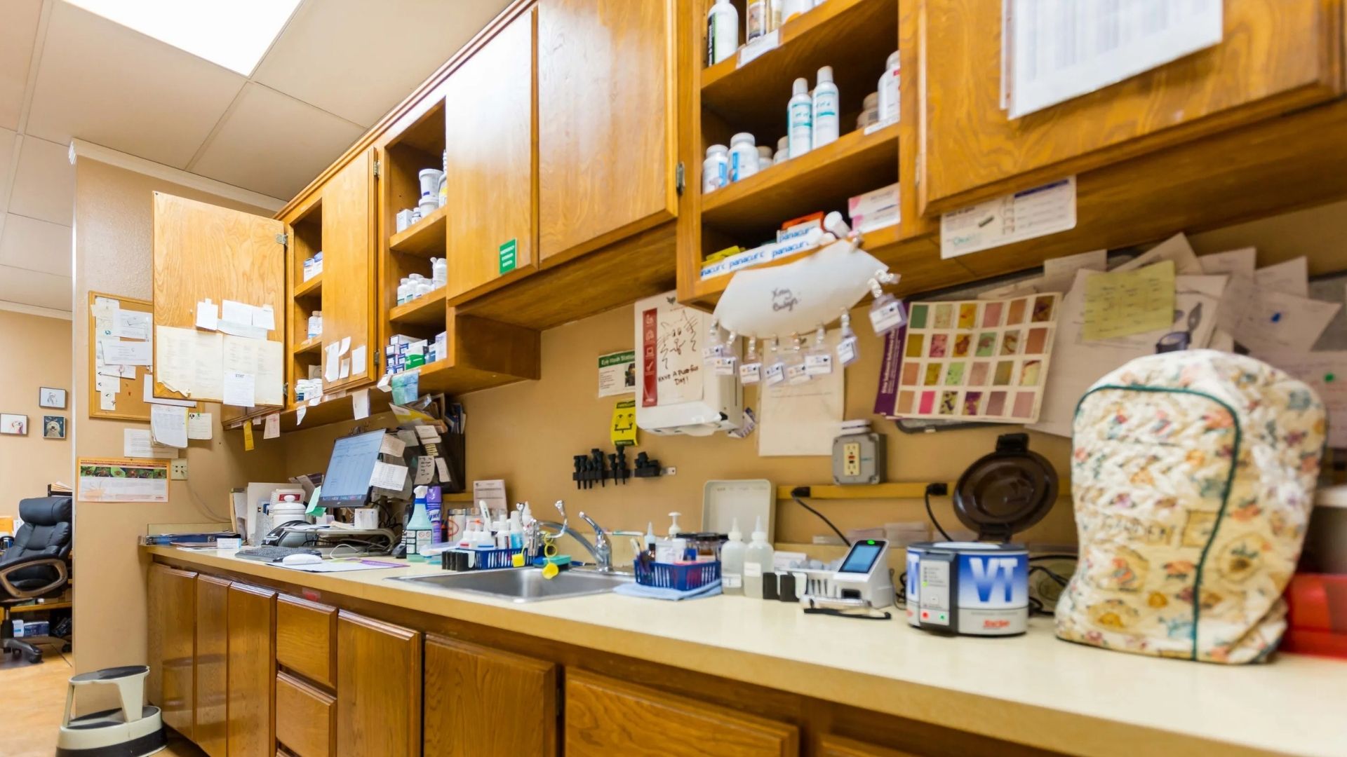 Lab testing place Interior of a small workshop with wooden shelves stocked with bottles and supplies, a long countertop with tools and containers, a corkboard covered in notes, and a cushioned chair along the wall.
